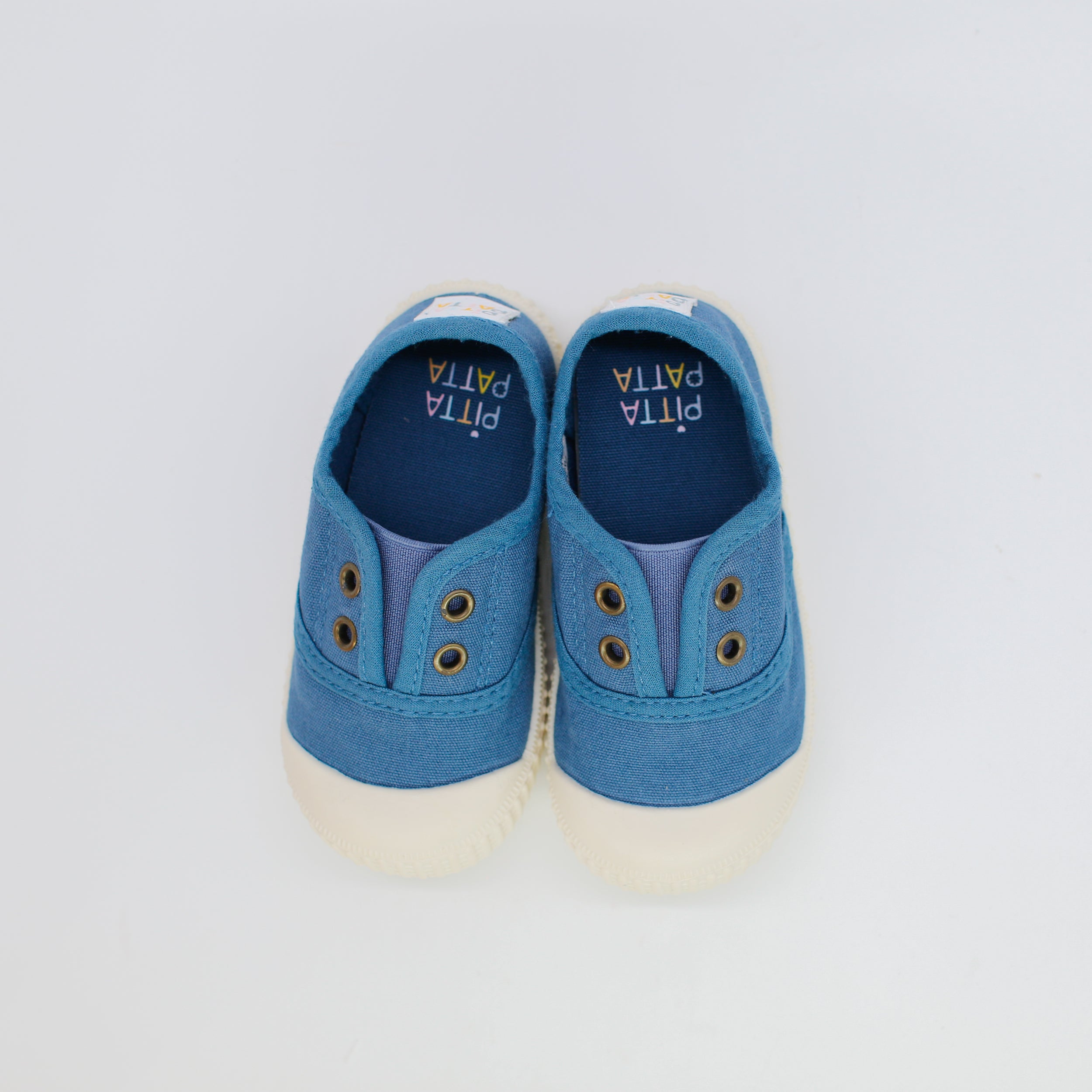 Pair of blue children's shoes with white soles on a light gray background