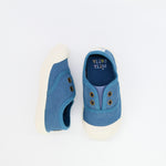 Pair of blue children's shoes with white soles on a light gray background
