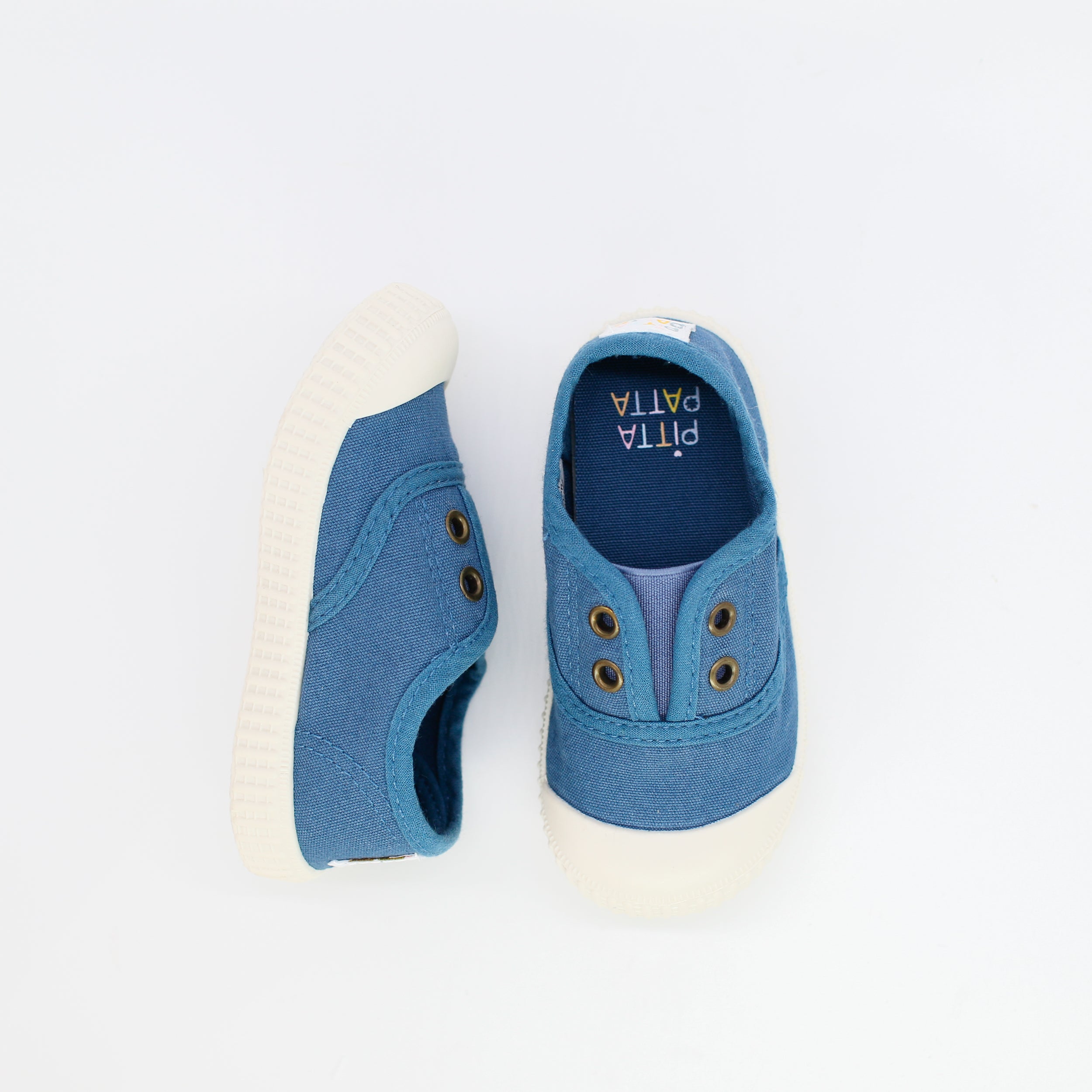 Pair of blue children's shoes with white soles on a light gray background
