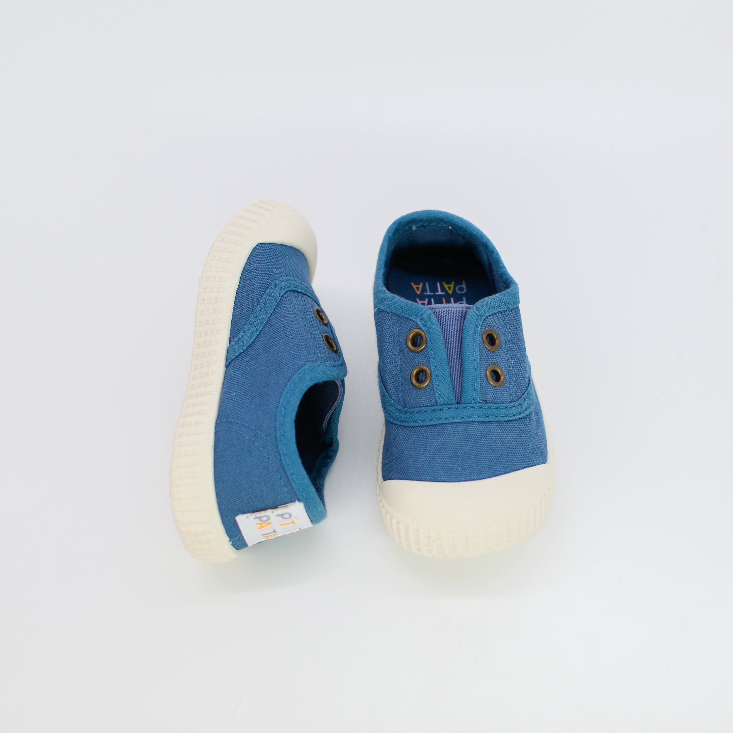 Pair of blue children's shoes with white soles on a light gray background