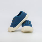 Pair of blue children's shoes with white soles on a light gray background