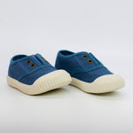 Pair of blue children's shoes with white soles on a light gray background