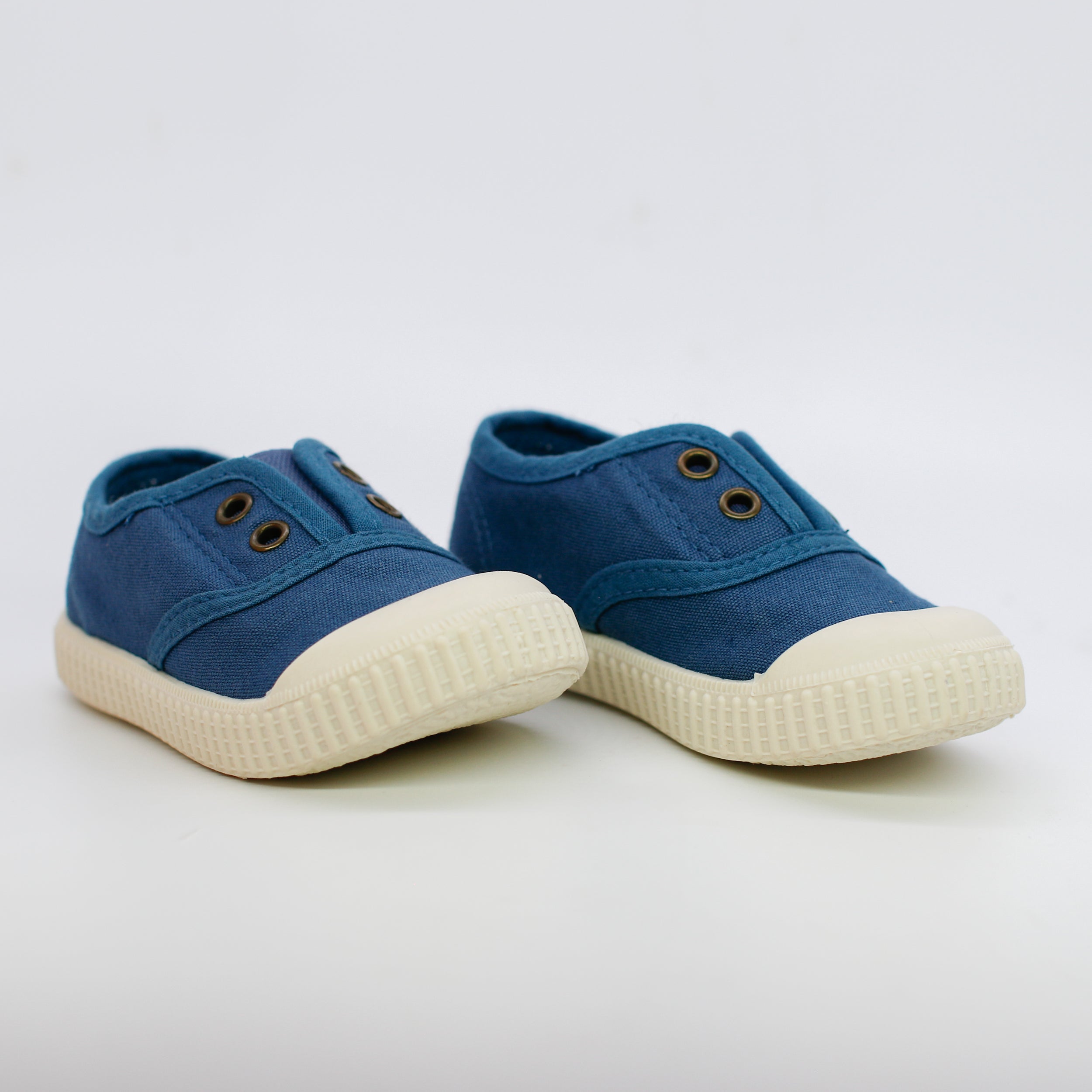 Pair of blue children's shoes with white soles on a light gray background
