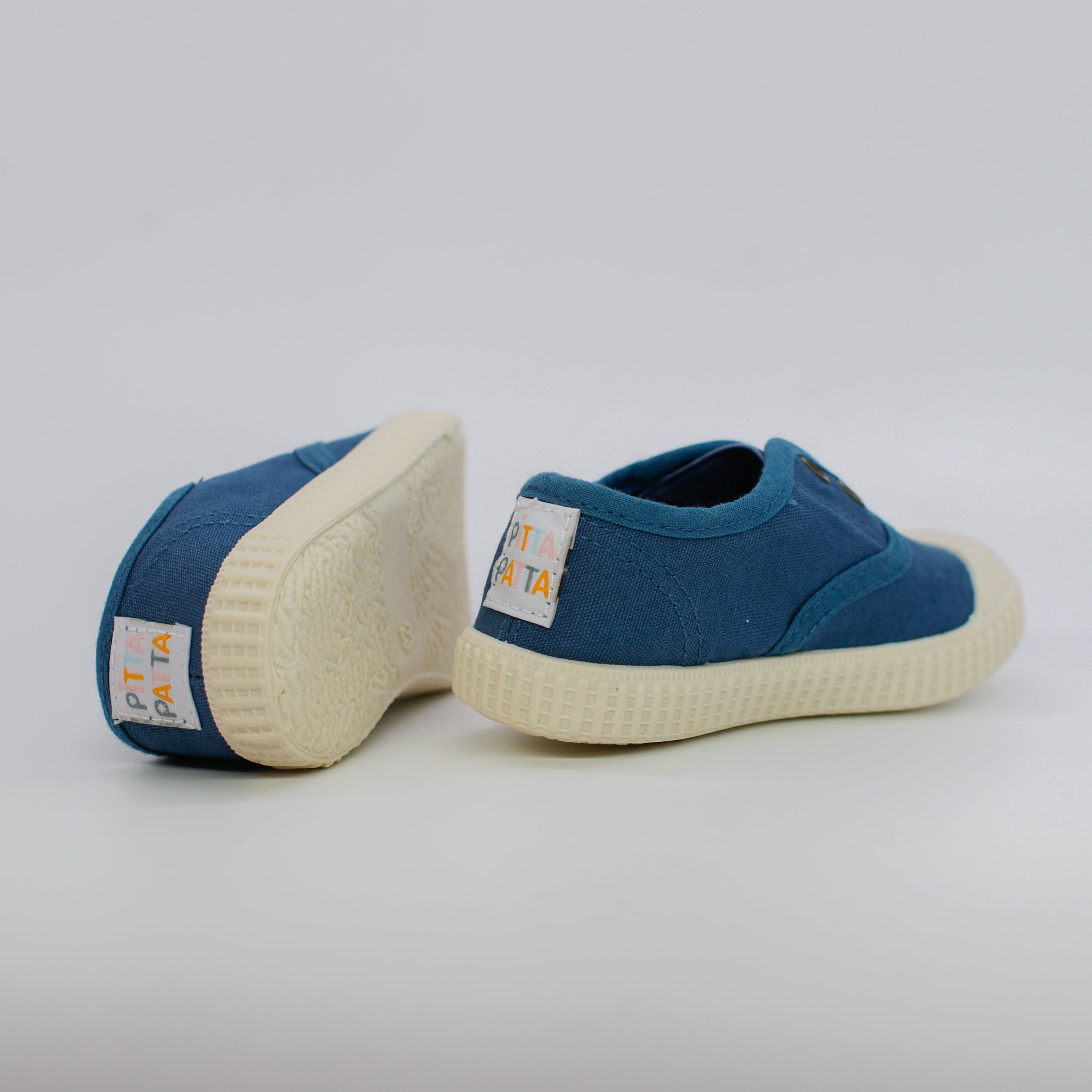 Blue children's shoes with white soles on a light gray background