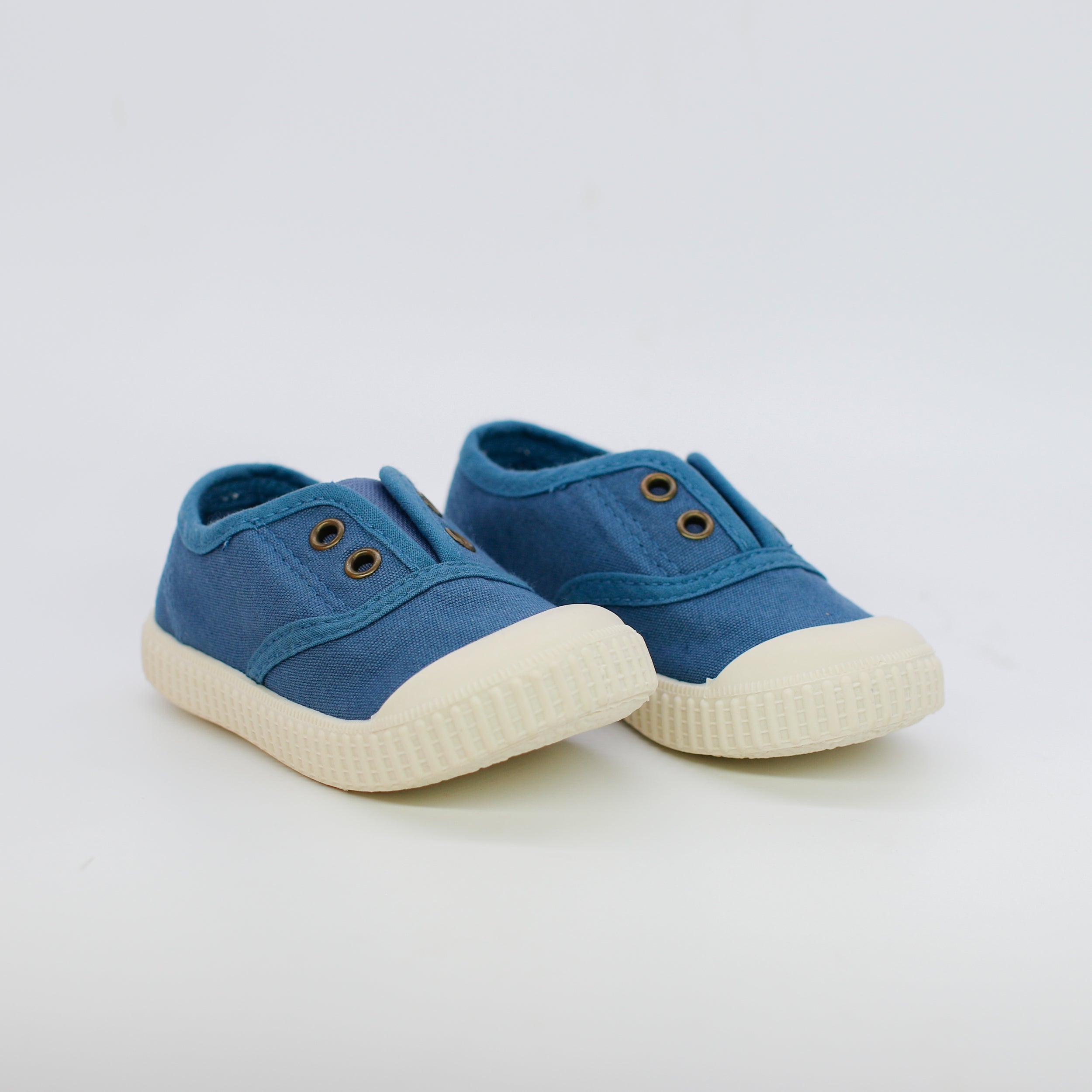 Pair of blue children's sneakers with white soles on a light gray background
