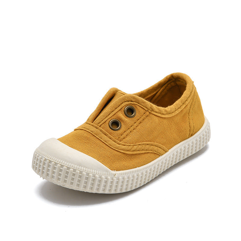 Yellow children's shoe with white sole on a white background